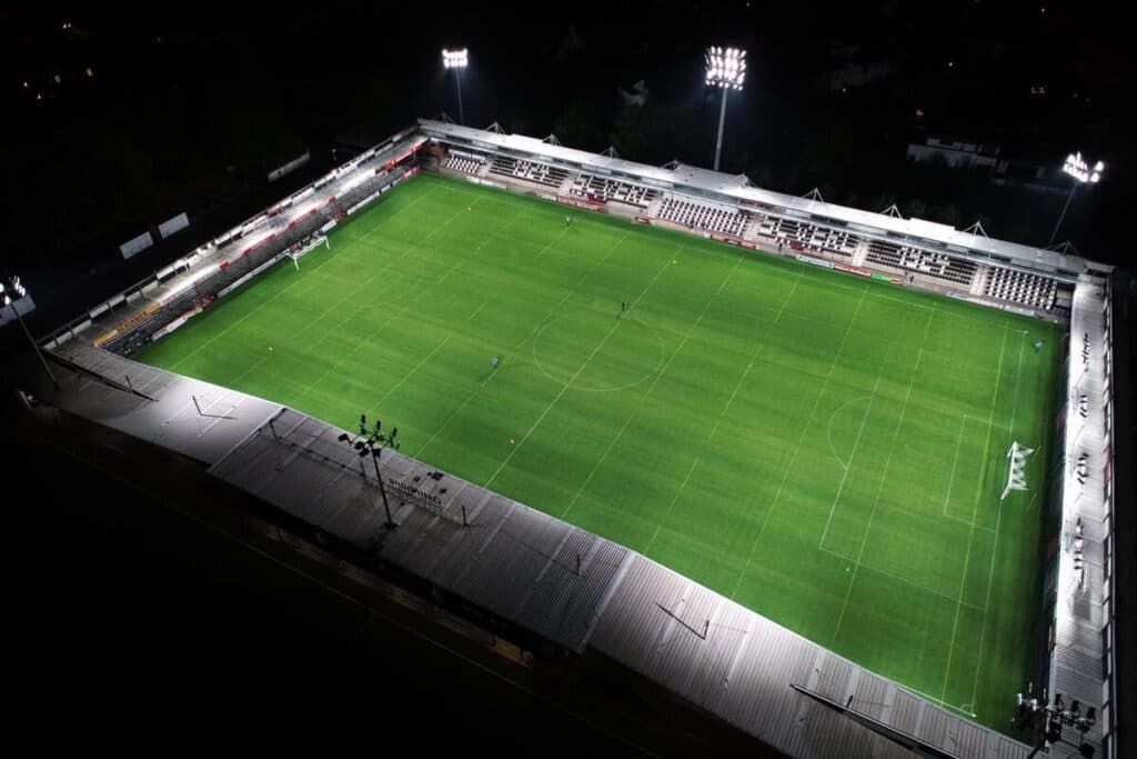 Luftaufnahme eines Sportplatzes bei Nacht unter Flutlicht