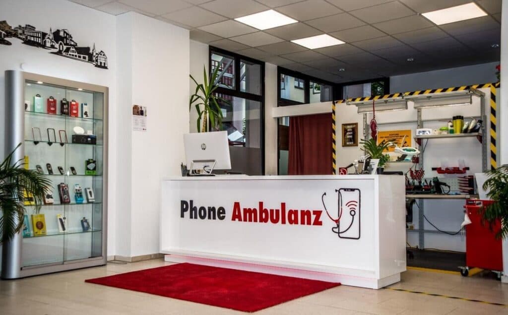 Empfangstresen der Phone Ambulanz mit Logo und Reparatur-Werkbank im Hintergrund